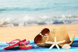 A pair of sunglasses and sandals on the beach